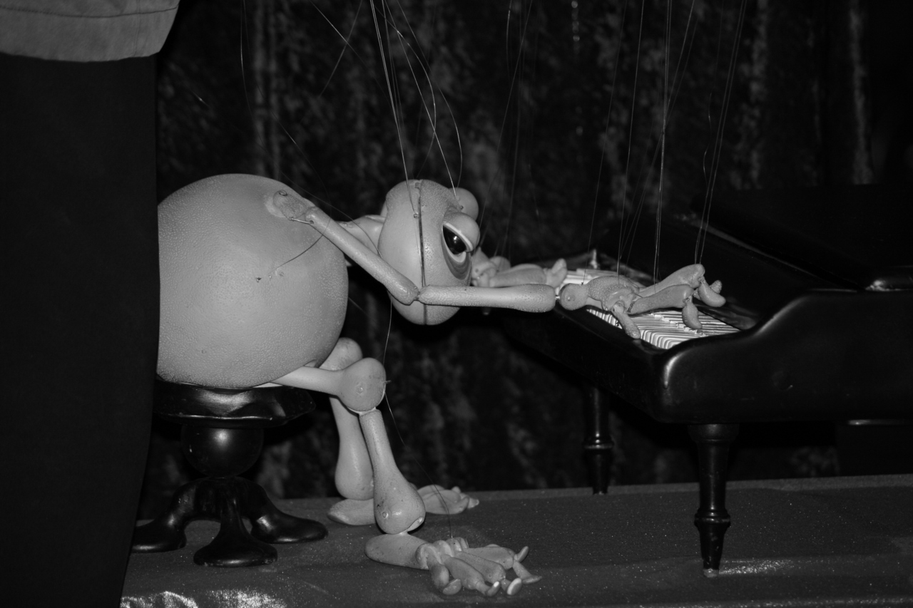 Photo description: A puppet frog playing the piano.