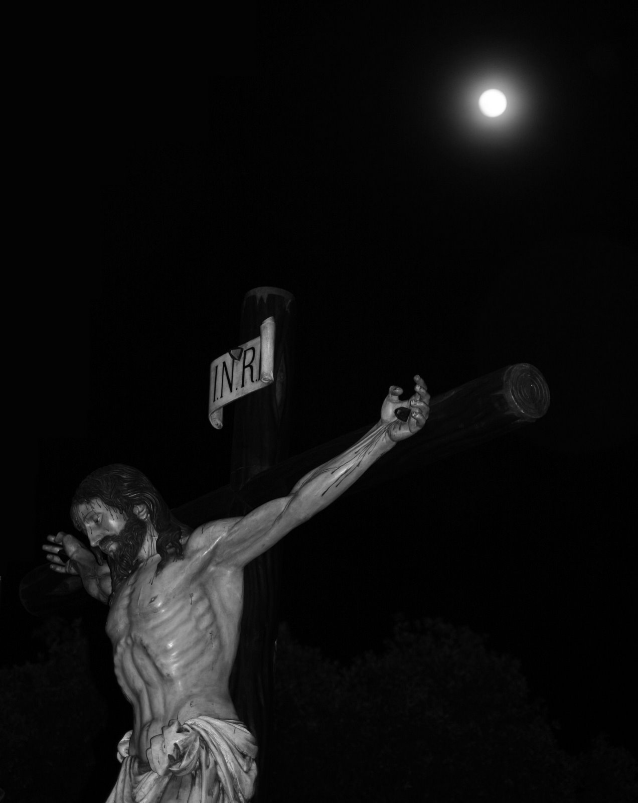 Photo description: Figura de Jesucristo crucificado, de noche, con la Luna de fondo.