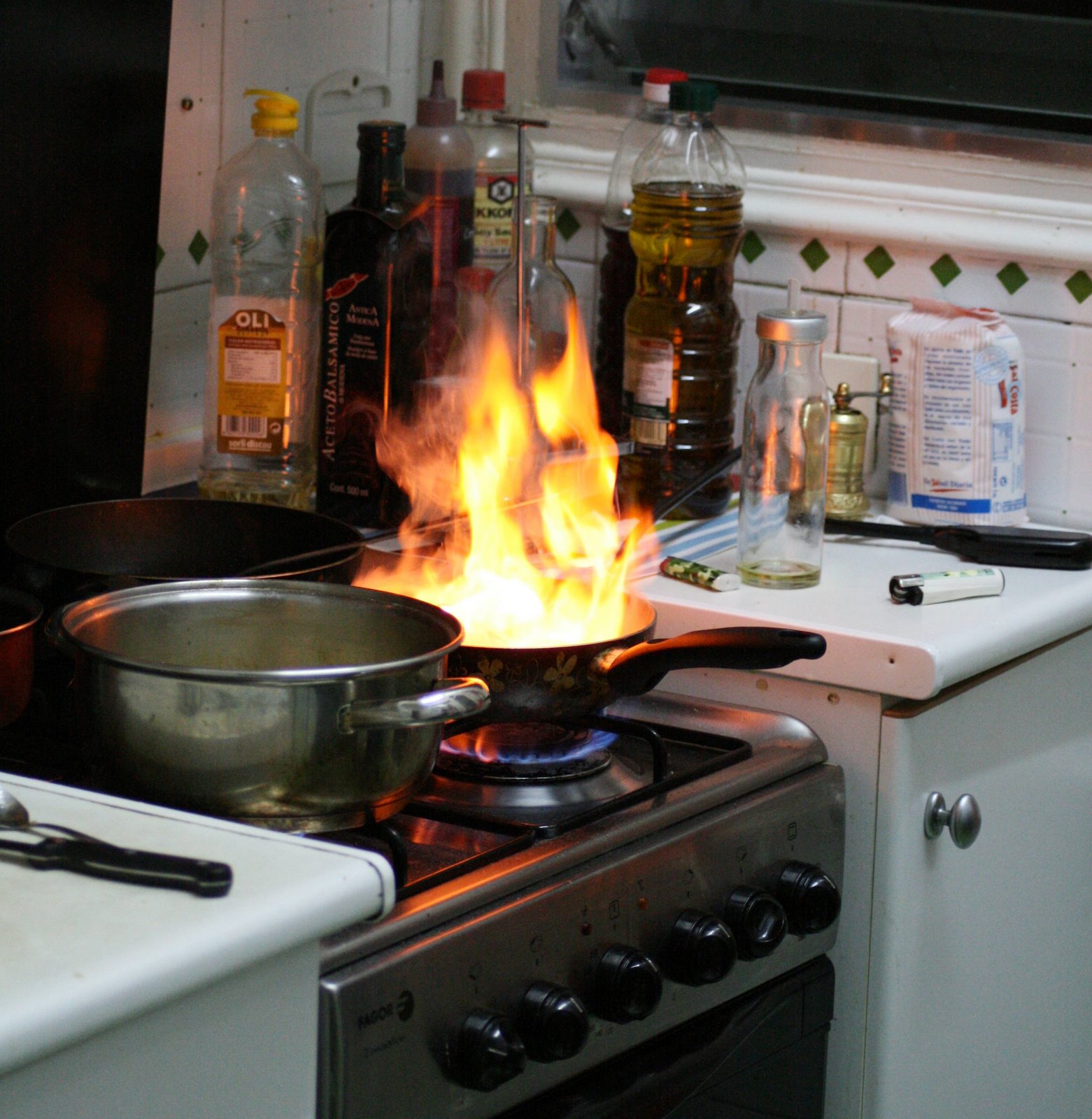 Photo description: Sartén en hornilla desprendiendo una gran llama de fuego.